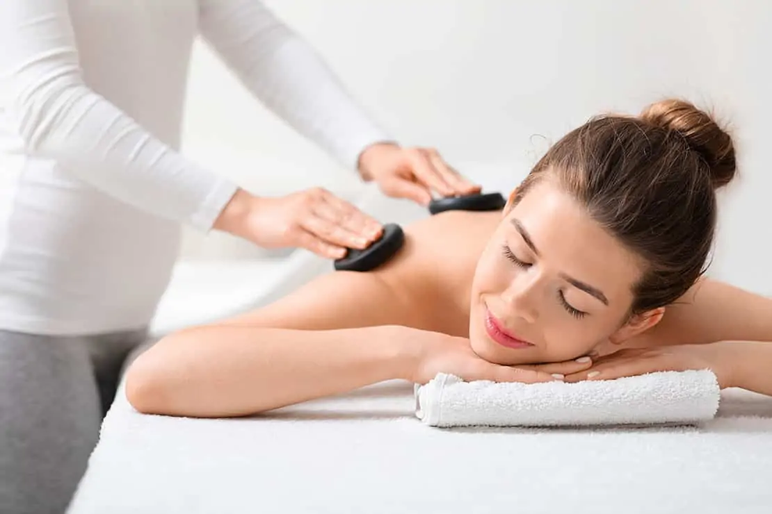 Frau erhält in einem Wellness-Spa eine Rückenmassage mit heißen Steinen.