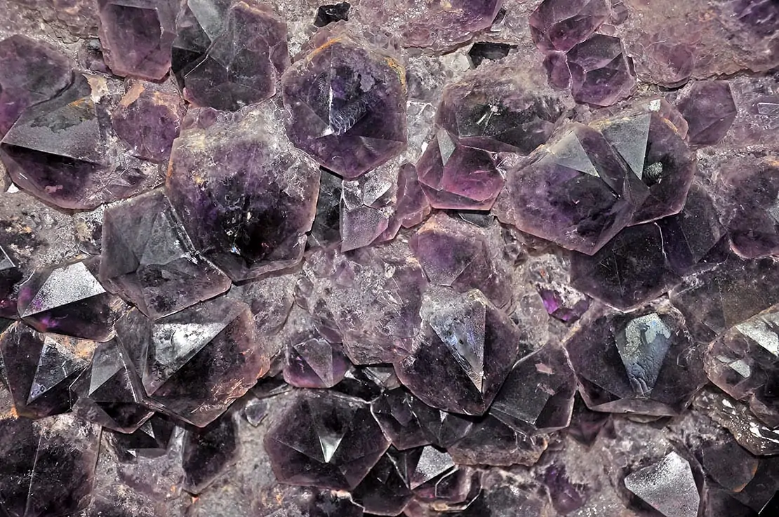 Eine Nahaufnahme eines Clusters von natürlichen lila Amethyst-Kristallen und die Wirkung von Wassersteinen.