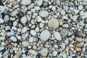 Verschieden große Kieselsteine an einem Strand, doch giftige Mineralien gehören nicht in Kinderhände!