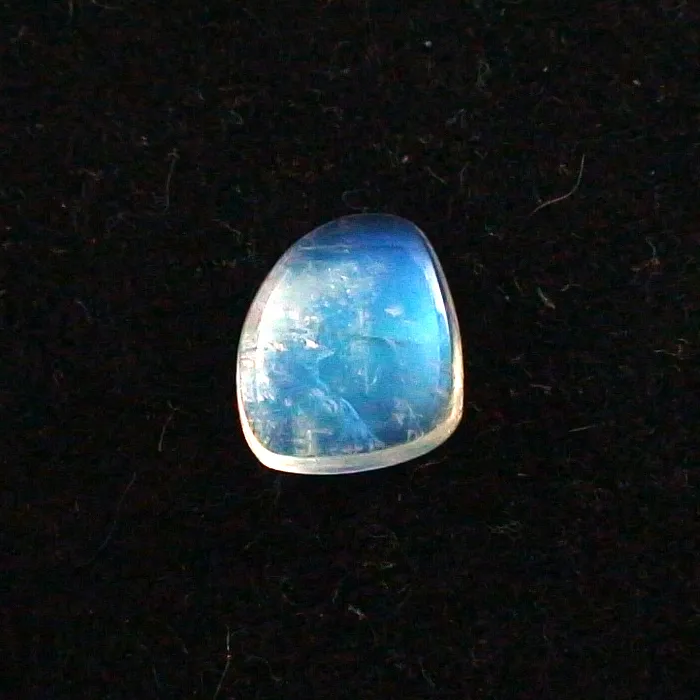 Ein halbtransparenter, polierter blauer Edelstein mit weißen Kanten auf schwarzem Hintergrund.