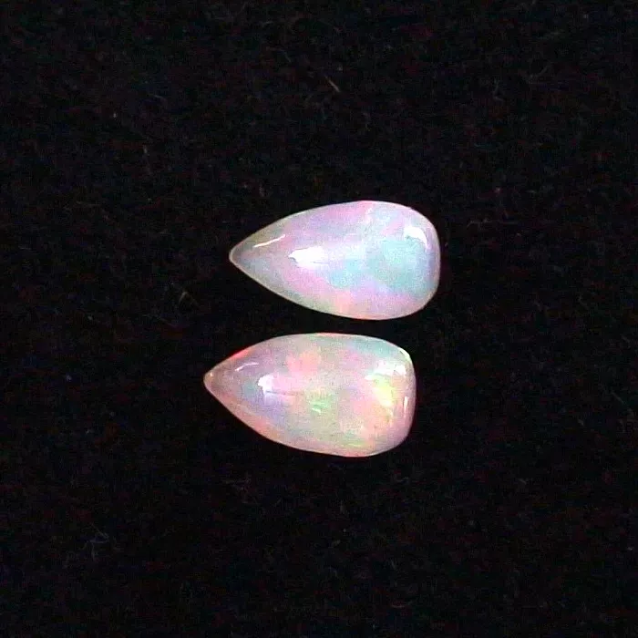 Auf einem schwarzen Hintergrund sind zwei birnenförmige Opal-Edelsteine mit schillernden Farben abgebildet.
