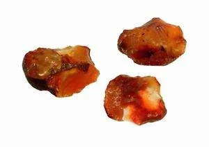 Drei unregelmäßig geformte Stücke eines rötlich-orangen Minerals mit weißen Flecken auf einem schlichten weißen Hintergrund.