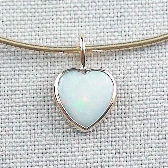 Herzförmiger Opalanhänger mit Goldfassung an einer Goldkette, platziert auf einem strukturierten grauen Hintergrund.