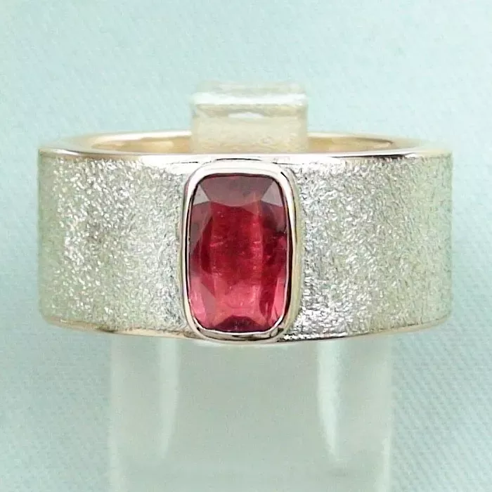 Ein Silberring mit breitem, strukturiertem Band und einem rechteckigen roten Edelstein in der Mitte.