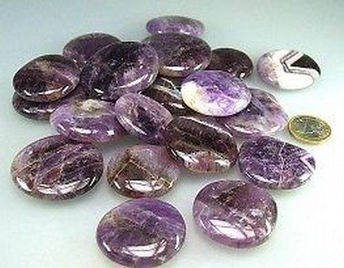 Eine Sammlung polierter Amethyststeine, die zum Größenvergleich neben einer Münze präsentiert werden.