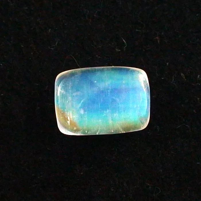 Ein rechteckiger, mehrfarbiger Opal-Edelstein auf schwarzem Hintergrund.
