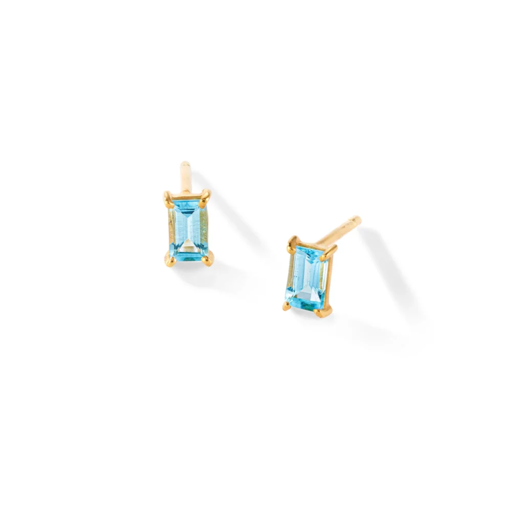 Ein Paar goldene Ohrstecker mit rechteckig geschliffenen blauen Edelsteinen auf weißem Hintergrund.
