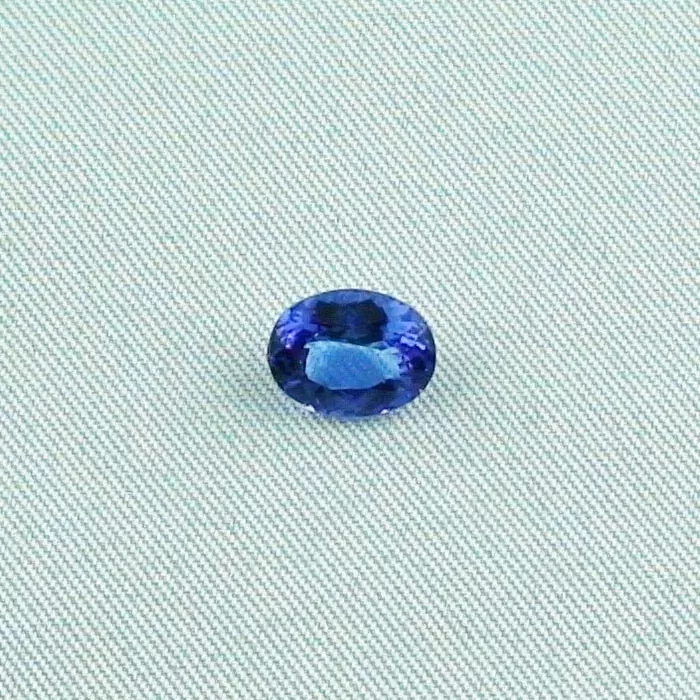 Ein runder blauer Edelstein auf einem hellen strukturierten Stoffhintergrund.
