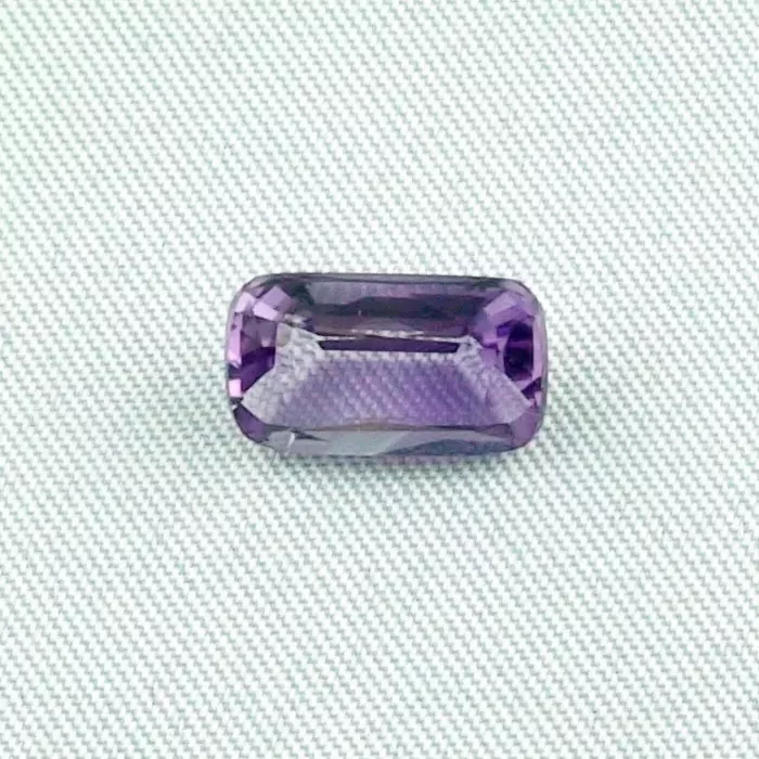Ein rechteckig geschliffener violetter Edelstein auf schlichtem weißen Hintergrund.