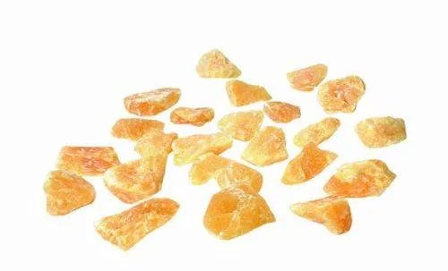 Mehrere unregelmäßig geformte orange Citrinkristalle, verstreut auf einem weißen Hintergrund.