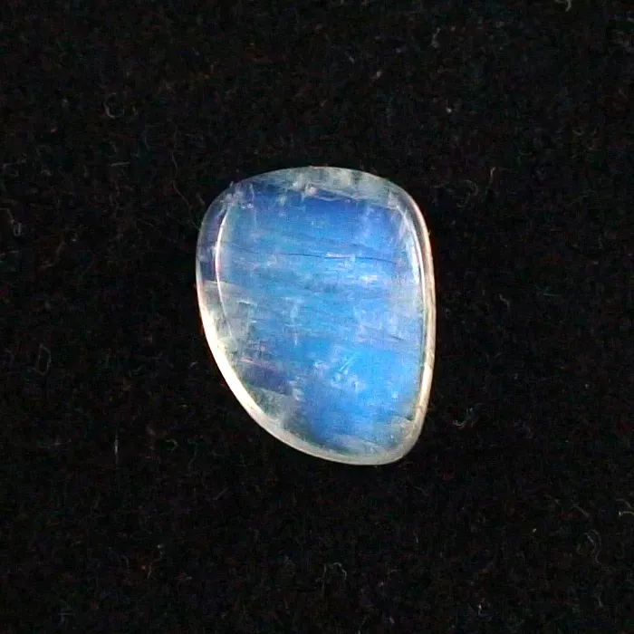 Vor einem schwarzen Hintergrund ist ein blauer, ovaler Edelstein mit reflektierender Oberfläche zu sehen.