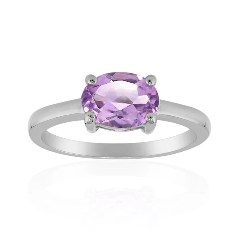 Silberring mit einem oval geschliffenen violetten Edelstein in einer Vierkrappenfassung vor weißem Hintergrund.